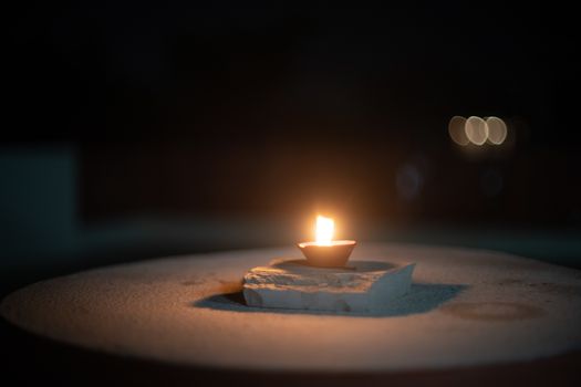 dark minimalistic image showing a diya oil lamp filled with oil or ghee and burning a cotton wick to produce a flame, its a popular religious item and decoration item on the hindu festival of diwali. This striking video shows it chasing away darkness in near total dark with plenty of copy space