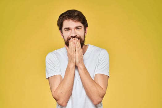 Bearded man white t-shirt emotions gestures with hands fun yellow background. High quality photo