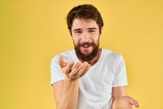 A man in a white t-shirt gestures with his hands lifestyle cropped view yellow background more fun. High quality photo