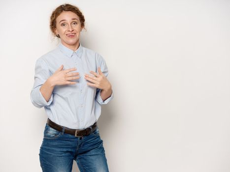 An elderly woman in a shirt shows her hands to herself on an isolated background