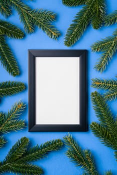 Christmas composition with empty picture frame. Fir branches decorations. Mock up greetings card template