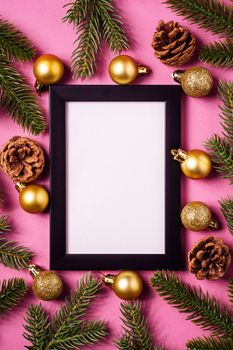 Christmas minimal composition with empty picture frame. Golden ornament, pine cones and fir branches decorations. Mock up greetings card template