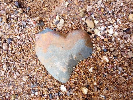 Natural stone in the shape of a heart on the river beach.