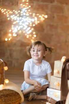.Adorable little girl sitting on the floor among the new year garlands.
