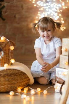 .Cute little girl sitting on the floor among the new year garlands.