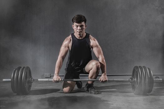 Strong fitness man doing arm workout with barbells in the gym