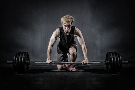 Strong fitness man doing arm workout with barbells in the gym