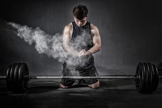 Strong fitness man doing arm workout with barbells in the gym