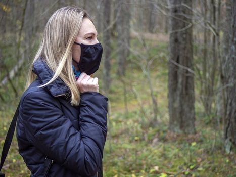 Beautiful european Women Wearing Protective Mask Outside Pretty young girl in medical black face mask in a forest. covid19 concept. modern reality. copy space. 2020, allergy. Autumn season. Copy space