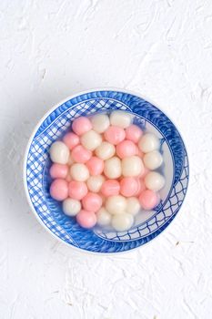 Top view of red and white tangyuan (tang yuan, glutinous rice dumpling balls) in blue bowl on white background for Winter solstice festival food.