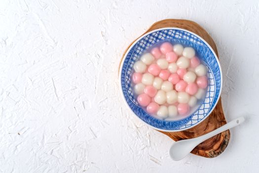 Top view of red and white tangyuan (tang yuan, glutinous rice dumpling balls) in blue bowl on white background for Winter solstice festival food.