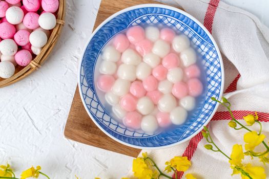 Top view of red and white tangyuan (tang yuan, glutinous rice dumpling balls) in blue bowl on white background for Winter solstice festival food.