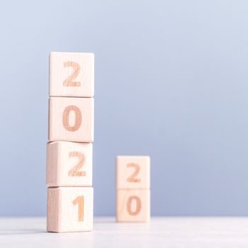 2021 New Year abstract design concept - Number wood block cubes isolated on wooden table and light mist blue background.