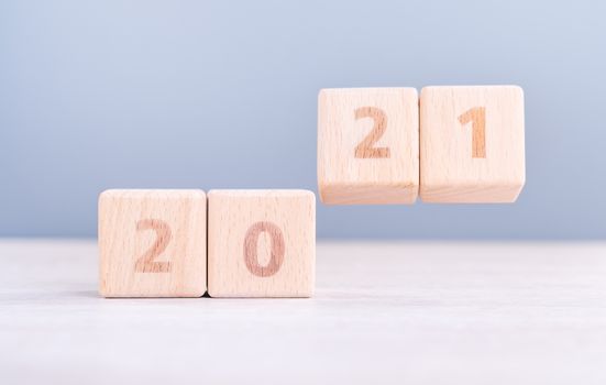 2021 New Year abstract design concept - Number wood block cubes isolated on wooden table and light mist blue background.