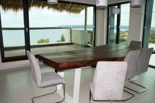 wooden table and chairs in the dining room overlooking the terrace and the sea.