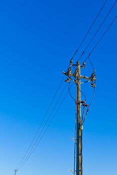 electric power sky lines and connections on a wooden post. Electric power lines and wires with blue sky. wooden electricity post against blue sky.