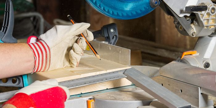 Carpenter work concept. Carpenter work with circular saw for cutting wood bar, the man sawed bars, construction and home renovation.