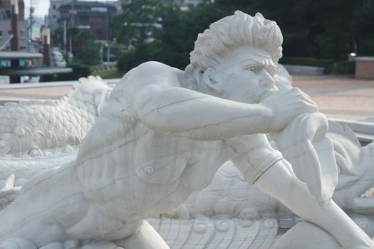 CHUNCHEON, SOUTH KOREA- October-03, 2020: sculpture of classical water god blowing conch shell - ancient natural trumpet. Stone sculpture of a Triton, blowing on his conch shell trumpet.