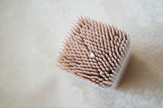 High angle top view of wood needles or wooden tooth picks arranged in a white plastic box container