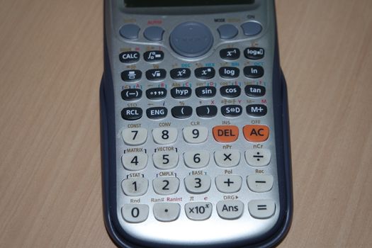 Calculator with colored keys or buttons isolated on a wooden background