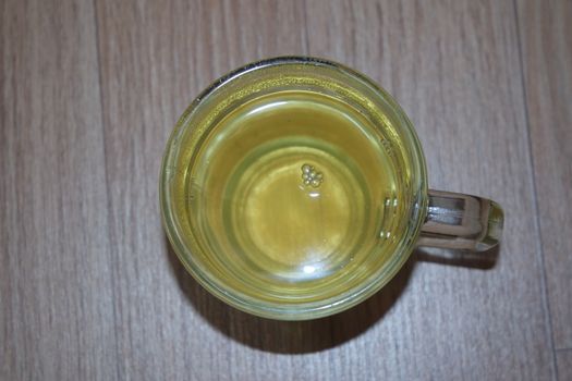 Glass cup having brewed fragrant green tea or qehwa or qahwa on the wooden floor. It is served with sugar or honey and nuts