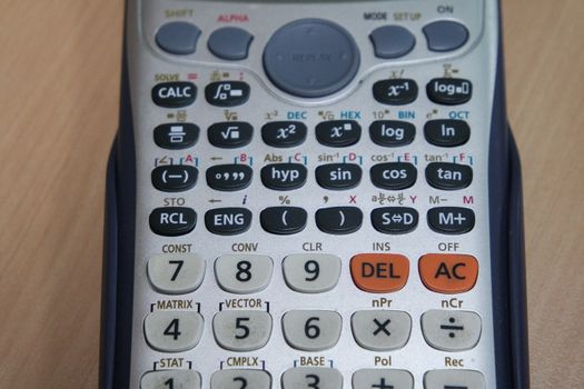 Calculator with colored keys or buttons isolated on a wooden background