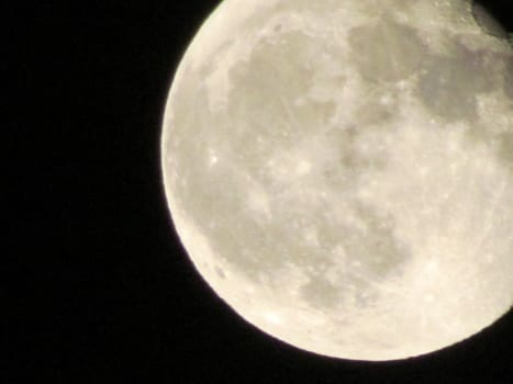 Earth's Moon Glowing On Black Background. The Moon close-up on a black night sky shot through a telephoto camera.