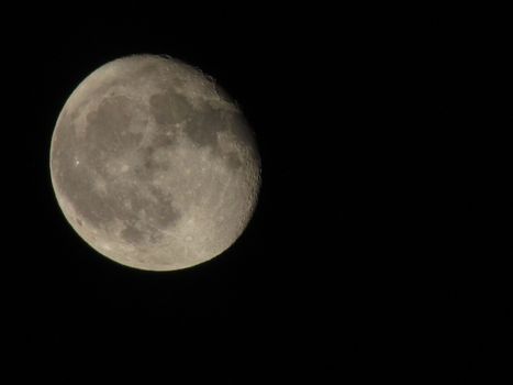 Earth's Moon Glowing On Black Background. The Moon close-up on a black night sky shot through a telephoto camera.