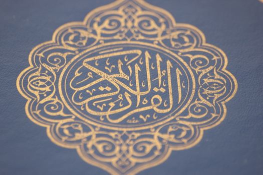 Closeup shot of Islamic Book Quran with golden arabic calligraphy that means Al-Quran, the Holy Quran