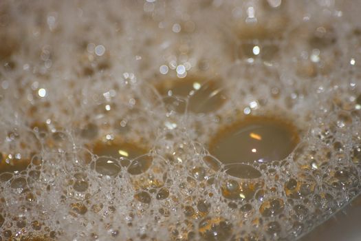 Closeup selective view of Foam and soap bubbles over water. white foam on water with brownish background