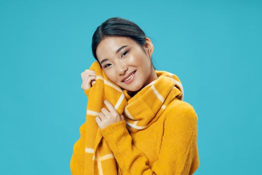 Woman covered herself with a yellow blanket cool smile asian appearance blue background
