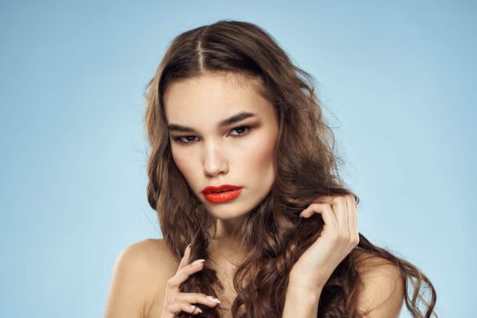 Brunette naked shoulders red lips fashionable hairstyle blue background. High quality photo