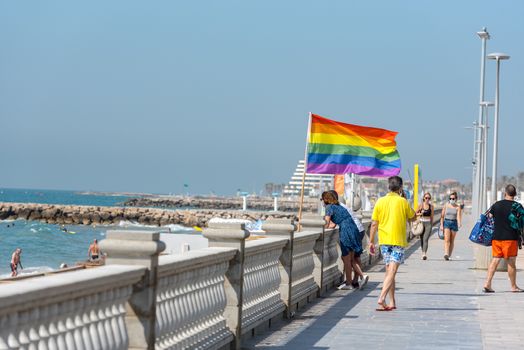 Sitges, Catalonia, Spain: July 28, 2020: Flag gay whit People on the Paseo Maritimo in the city of Sitges in the summer of 2020.