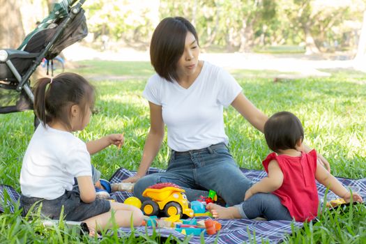 Beautiful young asian mom and daughter playing toy blocks for learning development happy and fun at park in summer, mother and kid cheerful activity together at garden in holiday, family concept.
