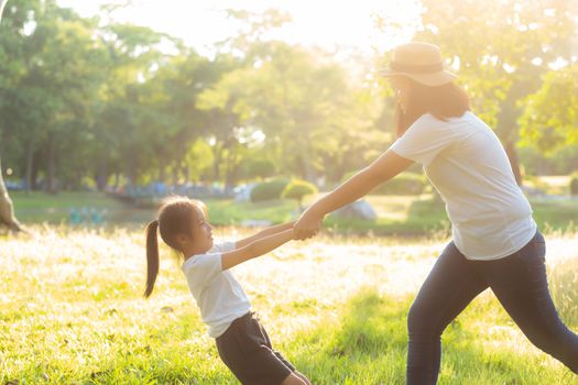 Young asian mother and little daughter playing the park with fun and happiness, family enjoy and relax and leisure together, mom and children smiling laughing in summer day.