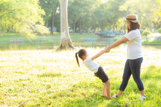 Young asian mother and little daughter playing the park with fun and happiness, family enjoy and relax and leisure together, mom and children smiling laughing in summer day.