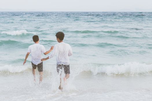 Homosexual portrait young asian couple running with cheerful together on beach in summer, asia gay going tourism for leisure and relax with happiness in vacation at sea, LGBT legal concept.