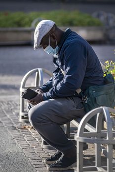 terni,italy november 11 2020:black man with medical mask sitting on a planter