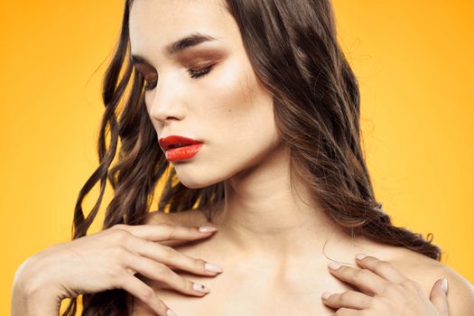 beautiful brunette red lips bare shoulders skin care yellow background. High quality photo