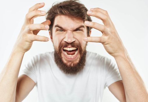 Emotional man gesticulates with his hands on a light background and a thick beard irritability. High quality photo