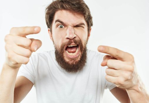 Emotional man gesticulates with his hands on a light background and a thick beard irritability. High quality photo