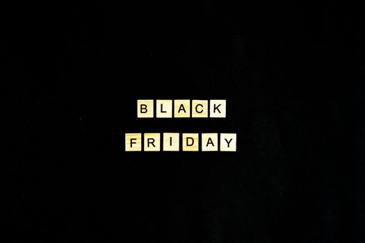Black Friday written in wooden letters on a black background, sales, holiday sales, top view, flat layout, price reduction.