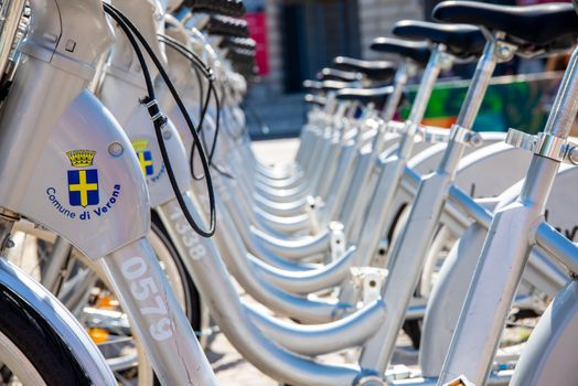 Verona, Veneto/Italy - 18.08.2020: A range of silver electric rental bicycles in Verona for rent to ride in the sun in the old town.