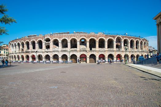 Verona, Veneto/Italy - 18.08.2020: The old and ancient amphitheater in Verona photographed from the outside with its decayed outer ring in front of a blue sky.