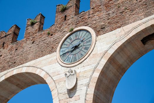 The clock of "I portoni della Brà" in Italy photographed from diagonally below, which is the entrance to Piazza Bra in Verona, which belongs to the old town and was built of old bricks and marble