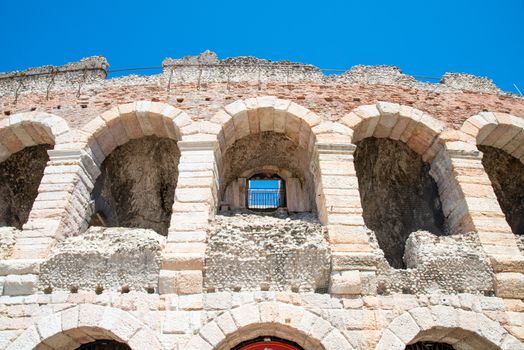 Several arches on the decayed external façade of the in amphitheater Verona with clear traces of decay and broken stones of marble and sandstone.