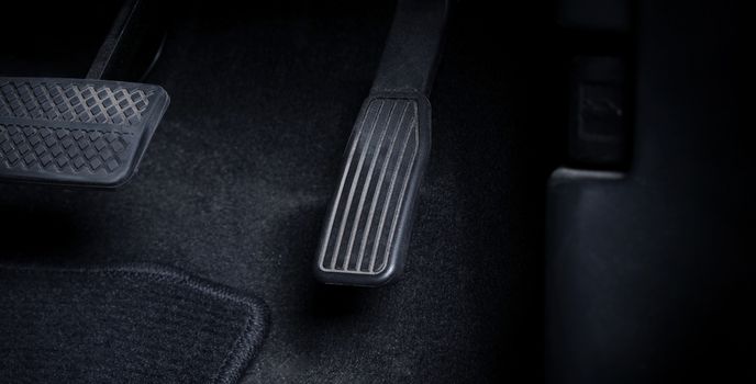 Close up images of man driving car by pushing accelerator and brake pedal with right foot black leather shoe and black jean pant. camera shot inside the japanese car.