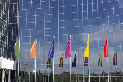 six multicolored flags against the background of the office building