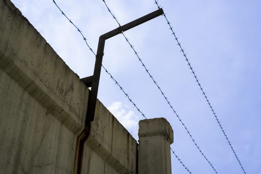 concrete fence with barbed wire against the blue sky