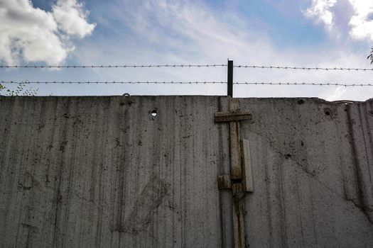 concrete fence with barbed wire against the blue sky